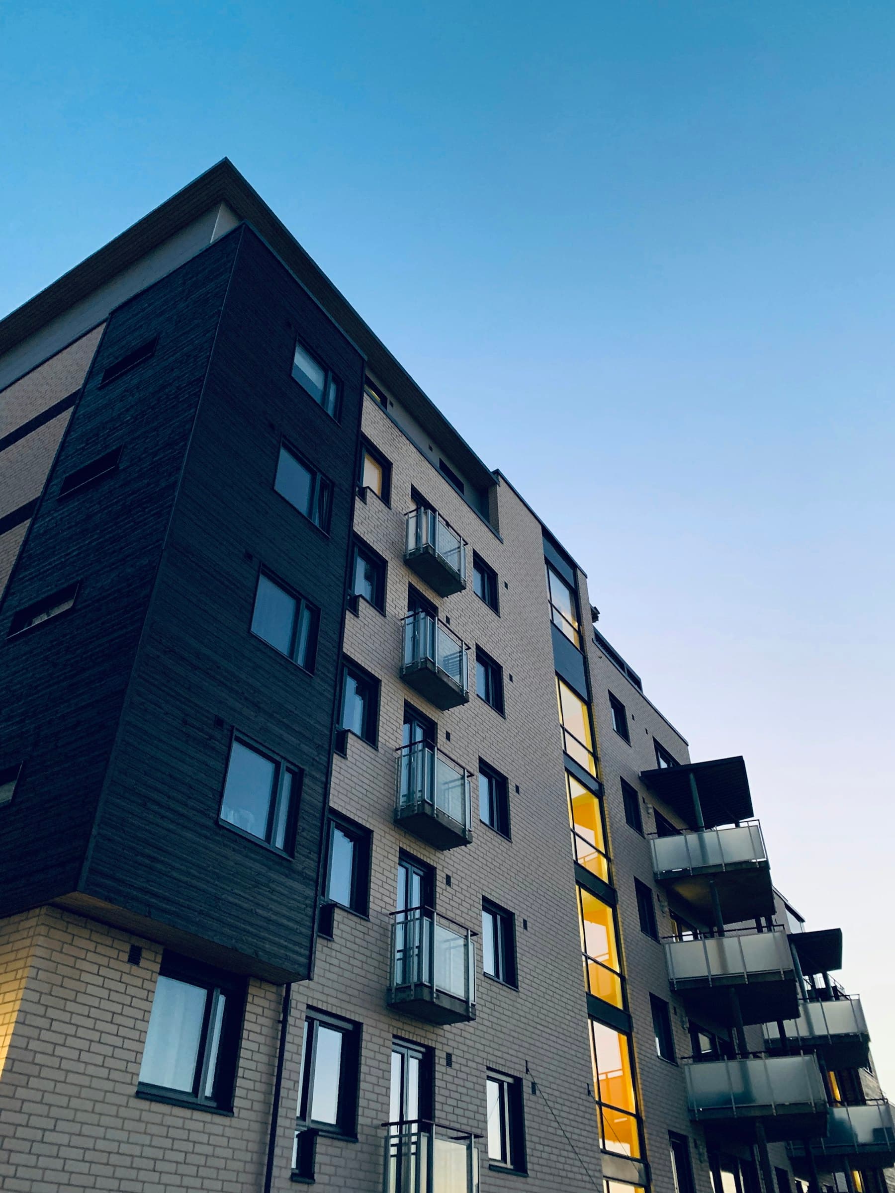 Mavi gökyüzü önünde balkonlu modern bir apartman cephesi